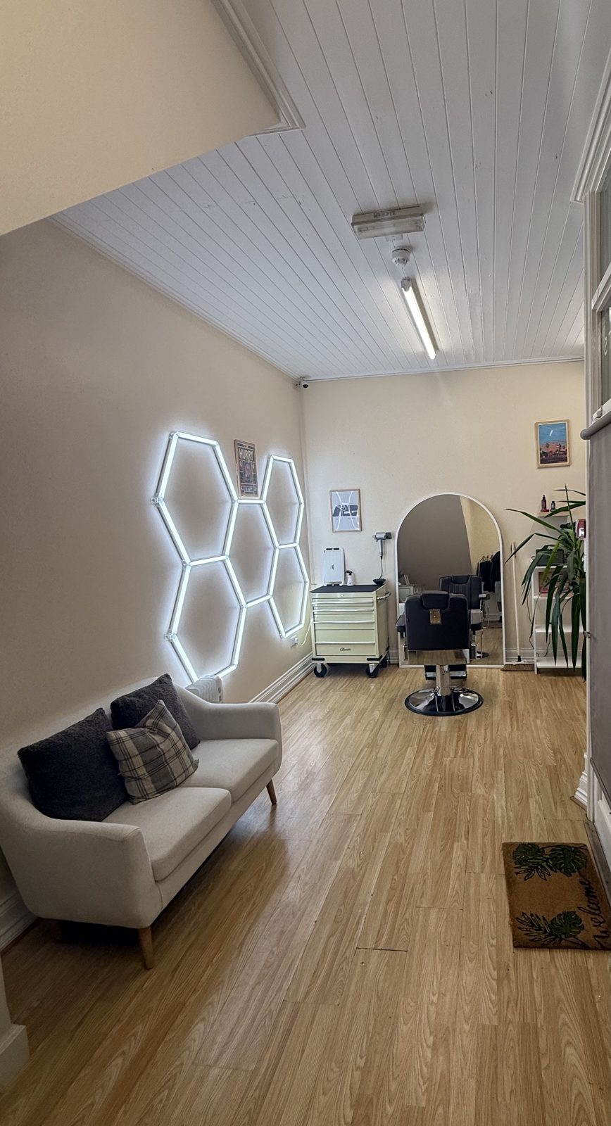 Inside PARROTTS: the hexagon light wall, a sofa and the barber chair by the arched mirror