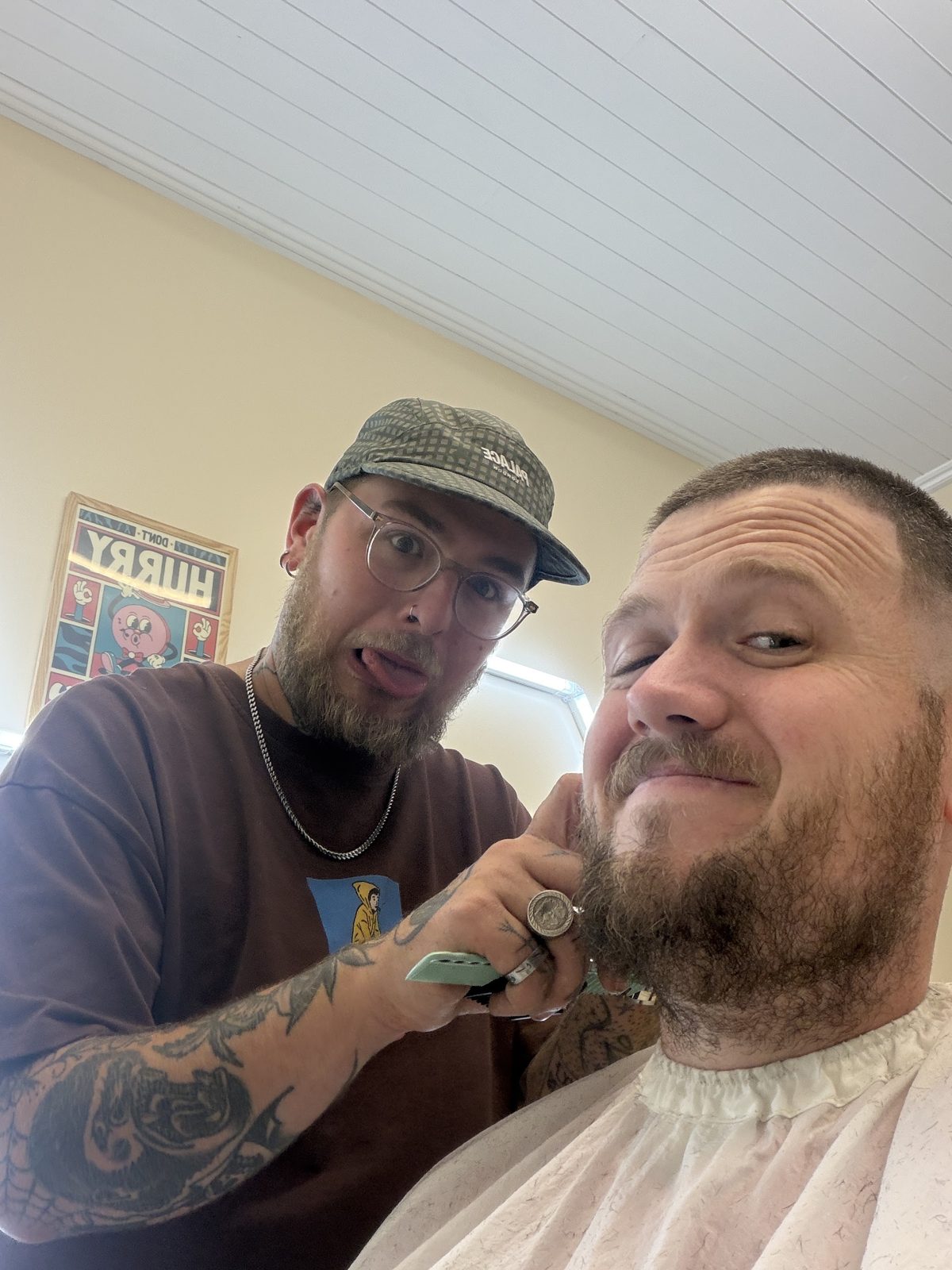 A customer grinning in the chair while his beard is trimmed