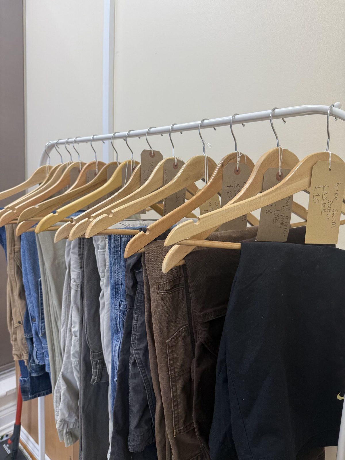 A rail of vintage trousers and jeans on wooden hangers in the shop